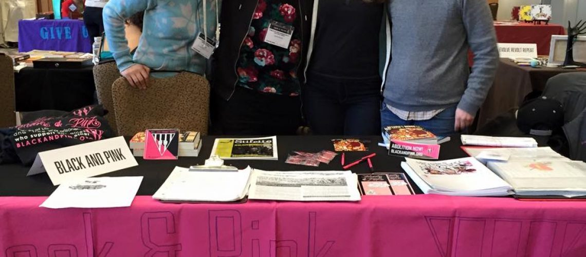 Four members of Black and Pink Chicago pose for a picture. They stand behind a pink table with the words 
