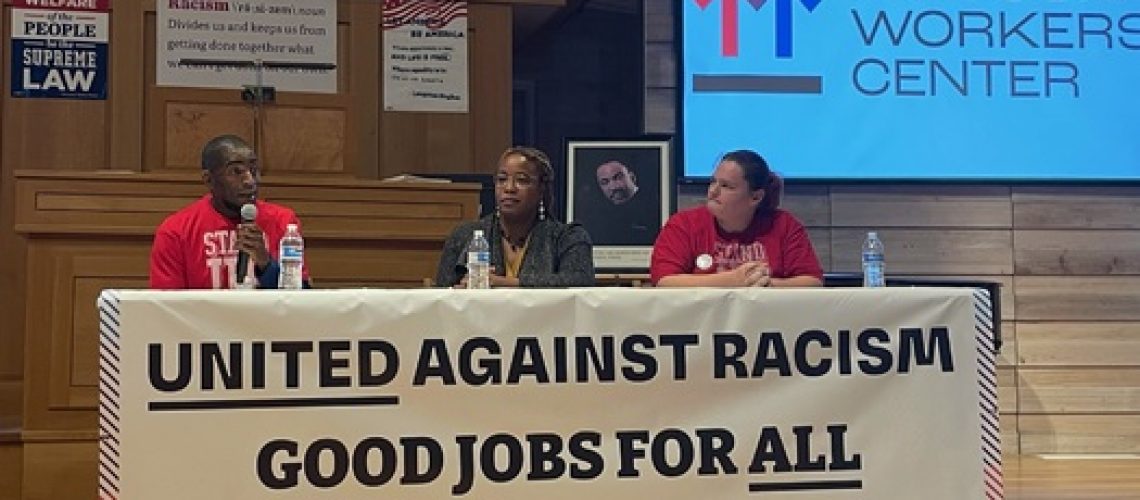 [ID: Three Missouri Workers Center members sit on a panel at a table where a large banner reads: 